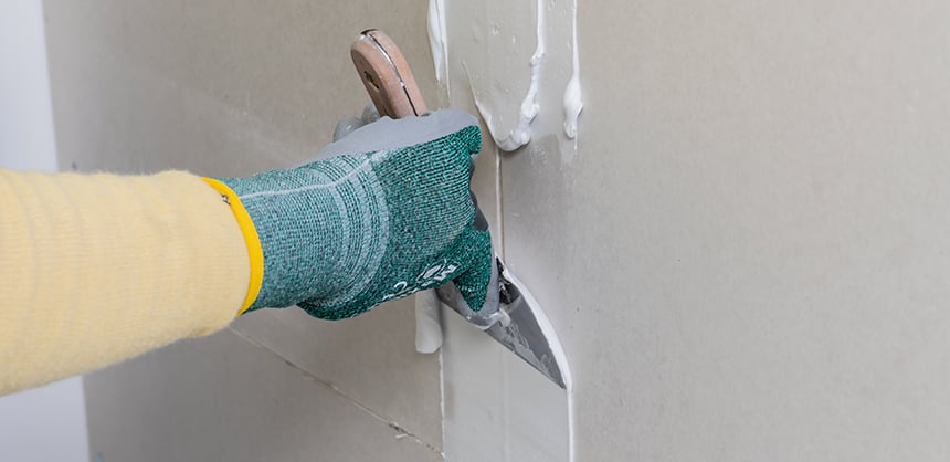 Profissional usando uma colher de pedreiro para passar argamassa